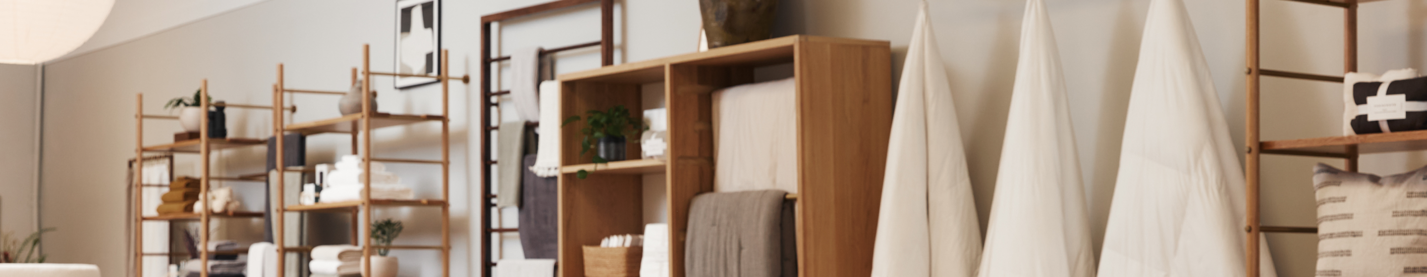 Shelving units in a retail store show various home goods on display. Blankets, towels, and decor. 